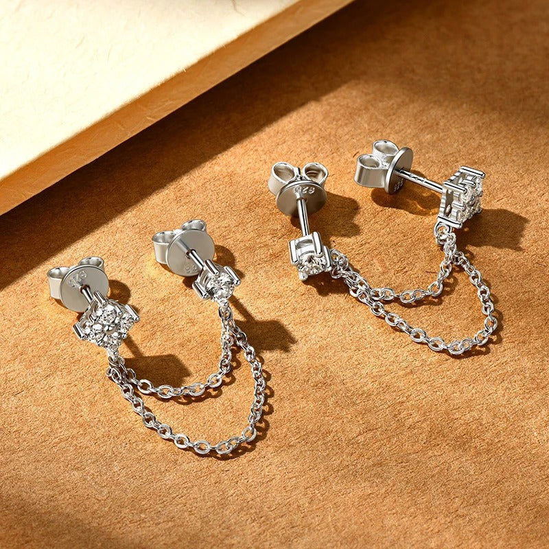 Moissanite stud earrings with delicate tassel chain drops in a polished silver setting, sparkling under soft light.